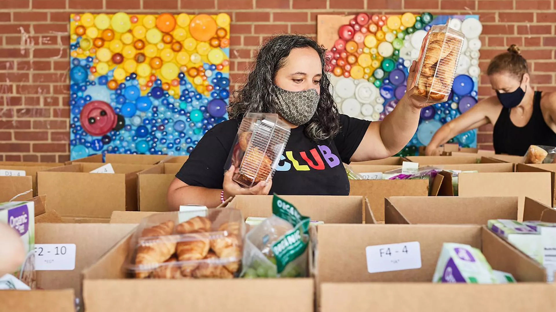 A woman loads groceries into cardboard boxes