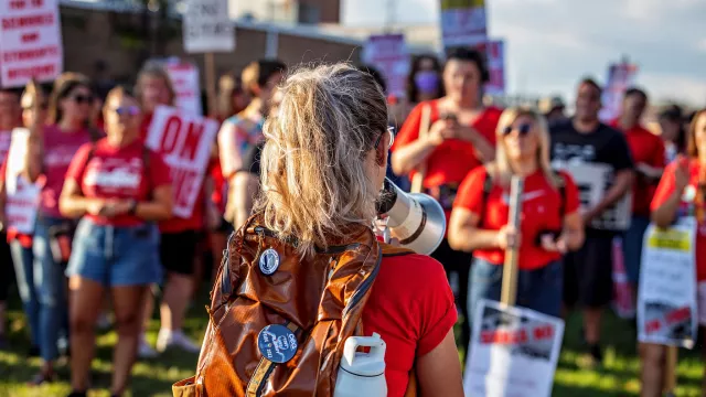 back of an educator with a bullhorn at a rally protest