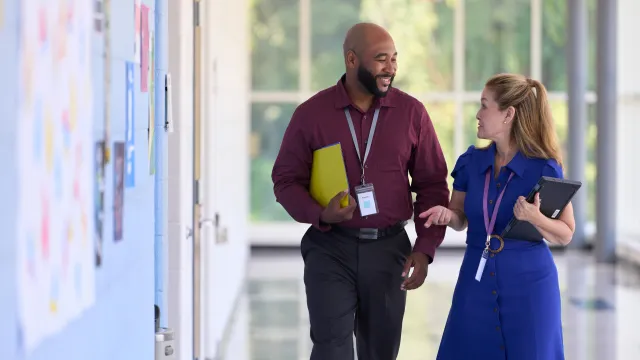 Two teachers walking down hallway