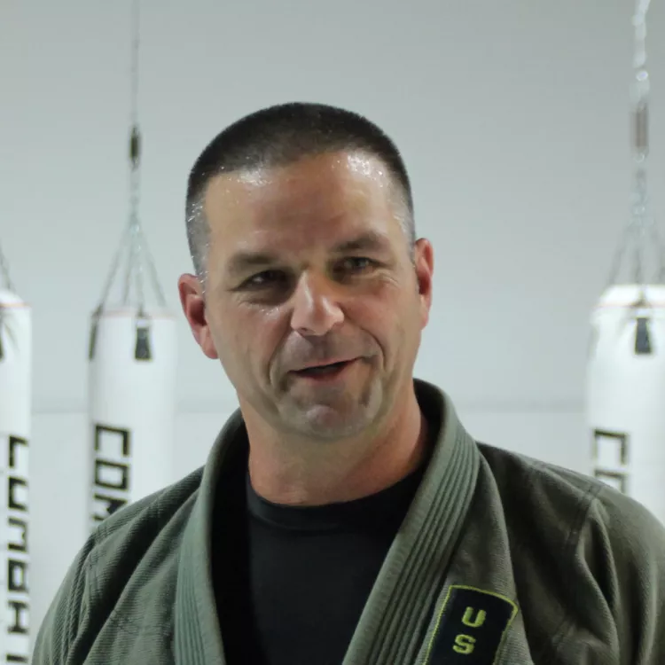 George Anderson stands in front of several punching bags.